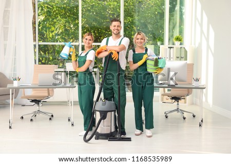 Team of janitors with cleaning supplies in office Royalty-Free Stock Photo #1168535989