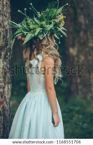 
A girl in a forest in a turquoise dress with a beautiful wreath