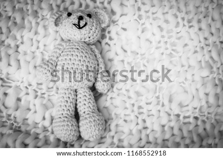 A soft teddy bear, toy for infant, isolated on a white blanket background. Sudden infant death syndrome stock image. Child death, abuse, harassment, rape, abort, abortion concept black and white image