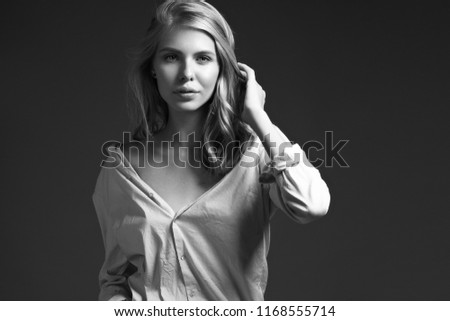 fashion model with long hair, beautiful eyes, perfect skin is posing in studio for glamour test photo shoot showing different poses. Picture taken in the studio on a gray background.
