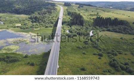 Aerial view of highway with trees and mountain. Clip. Top view of the asphalt road in forest area