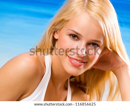Portait of happy smiling cheerful young beautiful blond woman on the beach