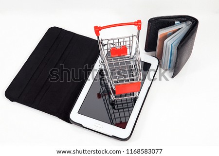 computer and small toy shopping cart on table. Internet shopping concept.