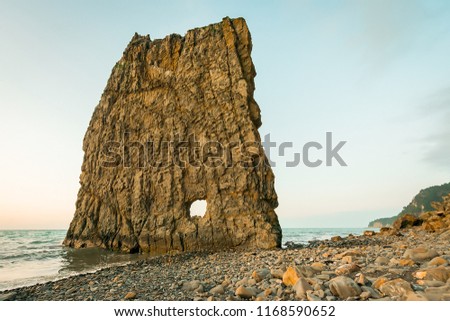Rock with a hole on the shore of the Black Sea Royalty-Free Stock Photo #1168590652