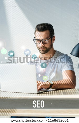 bearded developer working with laptop with SEO icons