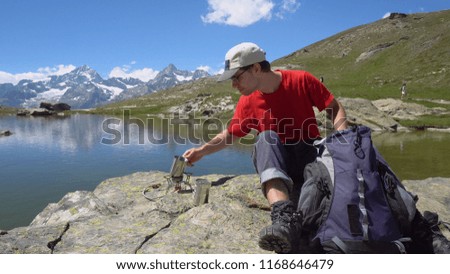 Happy Young Hiker Cooking Tea on Camping Stove