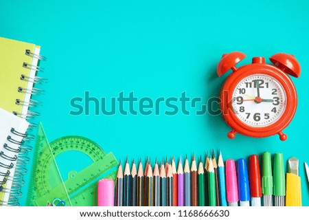 Back to school concept with school supplies and alarm clock on green background with copy space. Education