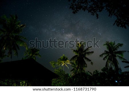 Night scene with silhouette hut and coconut tree with Milky Way Galaxy in sky.