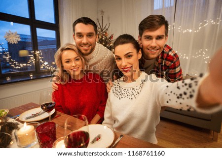 holidays and celebration concept - happy friends taking selfie at home christmas dinner