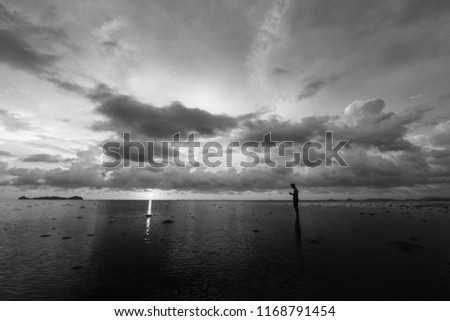 Black and white sunset scenery of  lonely man standing over the beach.