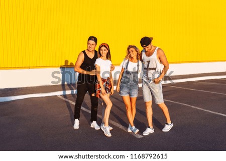 Beautiful cool young people posing on a yellow background, a group of young people resting and having fun, summer mood, friends walking in the city in a place