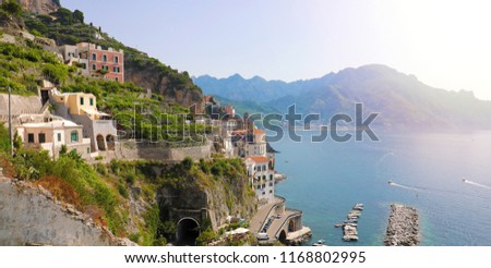 Stunning sunny day view of Atrani village overhanging the sea with green vineyards, Amalfi Coast, Italy