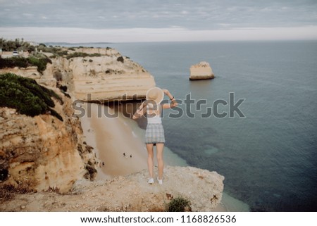 Woman enjoying great view on the rocky coastline during the sunrise in Lagos on the south of Portugal