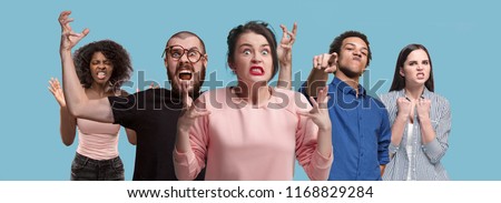What is it. The male and female portrait isolated on blue studio backgroud. Anger. Young, emotional, angry, scared people looking at camera. Human emotions, facial expression concept. Trendy colors Royalty-Free Stock Photo #1168829284