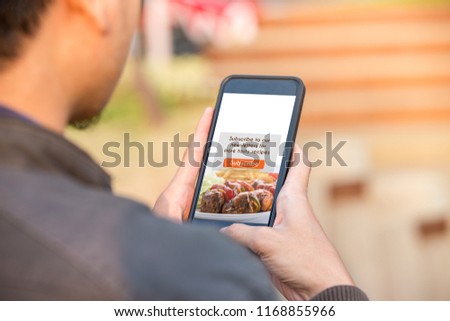 Food blog subscription concept. Man holding smartphone doing subscribe food blog on screen.