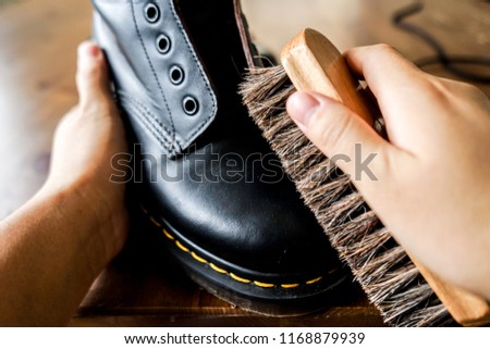 Cleaning leather boots with a shoe brush.  Royalty-Free Stock Photo #1168879939