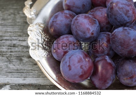 Ripe blue plums on wooden surface