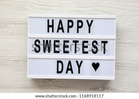 Modern board with text 'Happy Sweetest Day' word over white wooden surface, top view. From above, flat lay, overhead.  Royalty-Free Stock Photo #1168918117