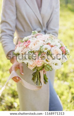 Young girl holding a beautiful spring bouquet. flower arrangement with garden roses. Color light pink. Bright dawn or sunset sun