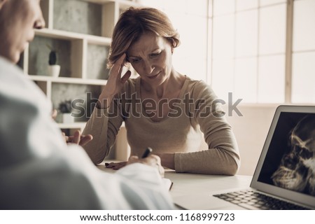 Female Patient with Ache at Doctor's Appointment. Radiologist Explain Middleaged Woman Diagnosis while Looking at X-ray Head Scan Picture at Laptop Screen. Medical Health Care Concept