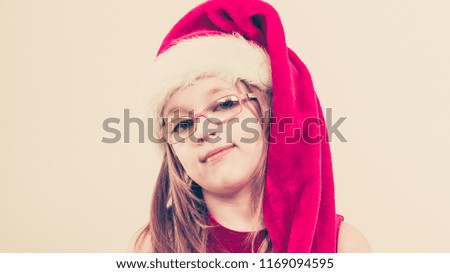 Christmas holiday concept. Toddler girl wearing Santa Claus hat and christmassy dress.