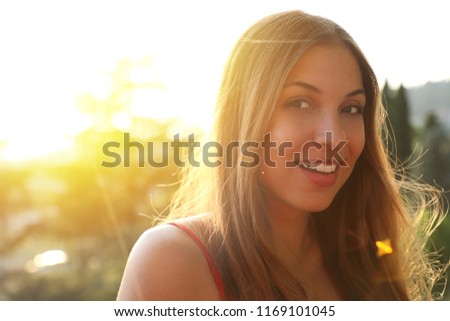 Portrait of smiling young woman with sunlight flare and copy space