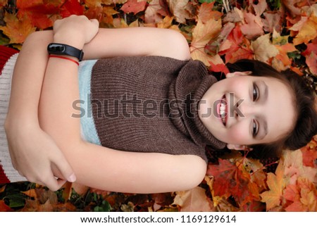 beauty, people, season and health concept - pretty little girl is lying in yellow Autumn leaves