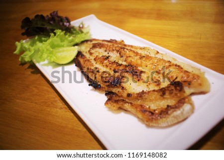 Grilled Dolly  Fish Sticks are placed in a white dish for eating.