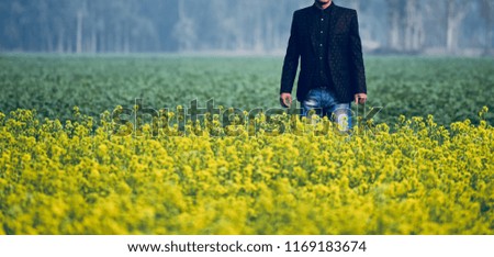 Standing man wearing stylish jeans around a mustard field unique photo