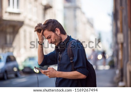 Image of young student using phone on the street