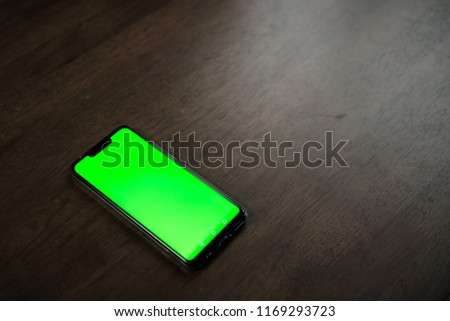 A slim borderless smartphone with Green Screen/Chroma Key on Brown table