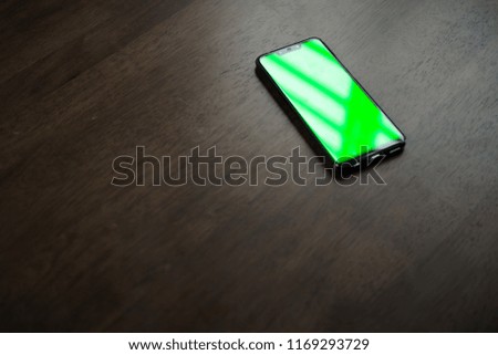 A slim borderless smartphone with Green Screen/Chroma Key on Brown table