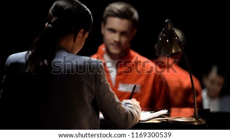 Female defense attorney writing accused prisoners statements for court, advocacy Royalty-Free Stock Photo #1169300539