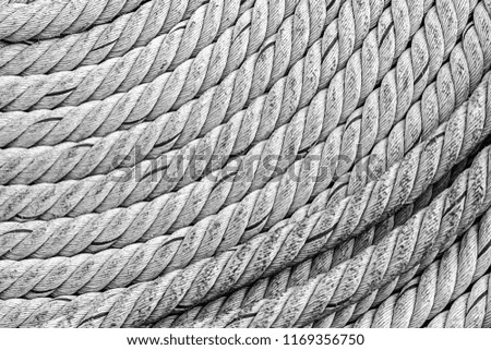 thick rope gray braided weathered old folded in a circle piece parallel lines rigid base marine design
