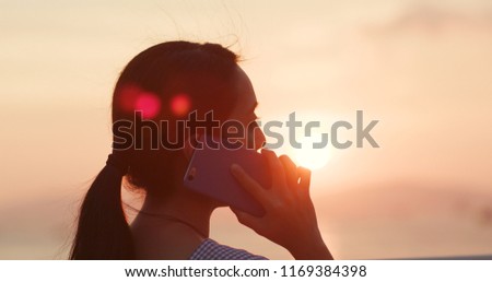 Woman talk to cellphone under sunset