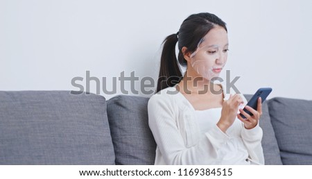 Woman apply paper mask on face and use of mobile phone