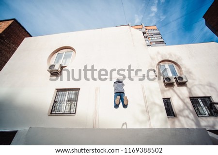 Teenage boy on a street in a big city next to a high-rise building alone. concept of a teenager parkour life. parkour jump on a building background from the back