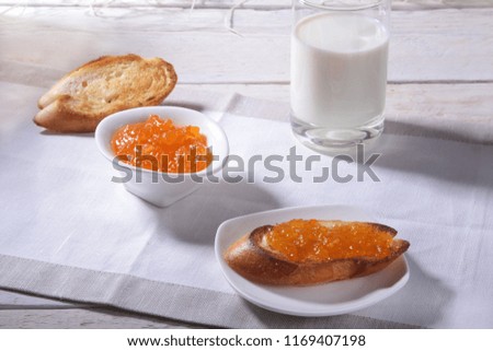 Morning Breakfast set with orange jam on bread toast and milk in glass.