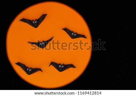 The Halloween origami (or Paper folding) of bats isolated on orange and black background with space for text.