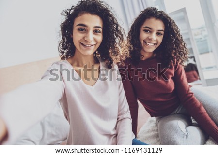 Show your smile. Happy females keeping smile on faces and looking straight at camera