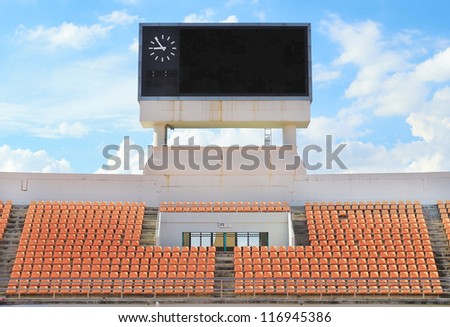 Scoreboard, orange seat in stadium with cloud and blue sky backg