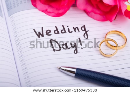 Two Golden Rings And Pen On Diary With Wedding Day Text