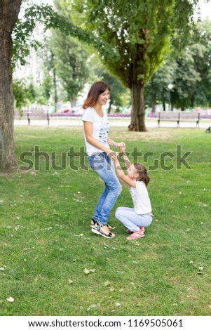 daughter and mother on the lawn.in a white t-shirt and jeans. a walk in the Park. child. mother daughter. summer.