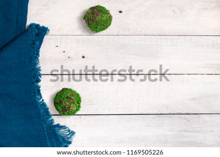 White wooden rustic background with moss balls and blue shabby cloth.