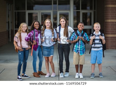 Large Group portrait of pre-adolescent school kids smiling in front of the school building. Back to school photo of a diverse group of children wearing backpacks and ready to go to school Royalty-Free Stock Photo #1169506729