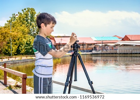 A young boy tries to install a smartphone on  professional camera  tripod