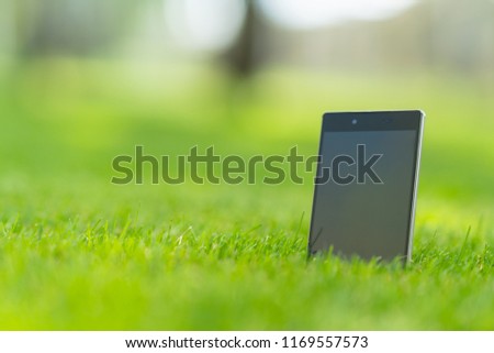 Blank tablet pc with a black screen with copy space standing upright in green grass in a low angle view