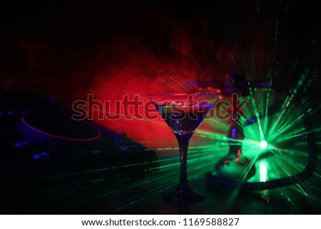 Glass with martini with olive inside on dj controller in night club. Dj Console with club drink at music party in nightclub with stylish oriental shisha