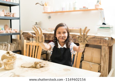 Portrait of confident girl showing dirty palms while learning pottery in class