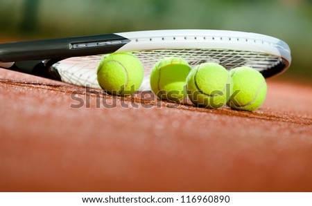 Close up of tennis racquet and balls on the clay tennis court